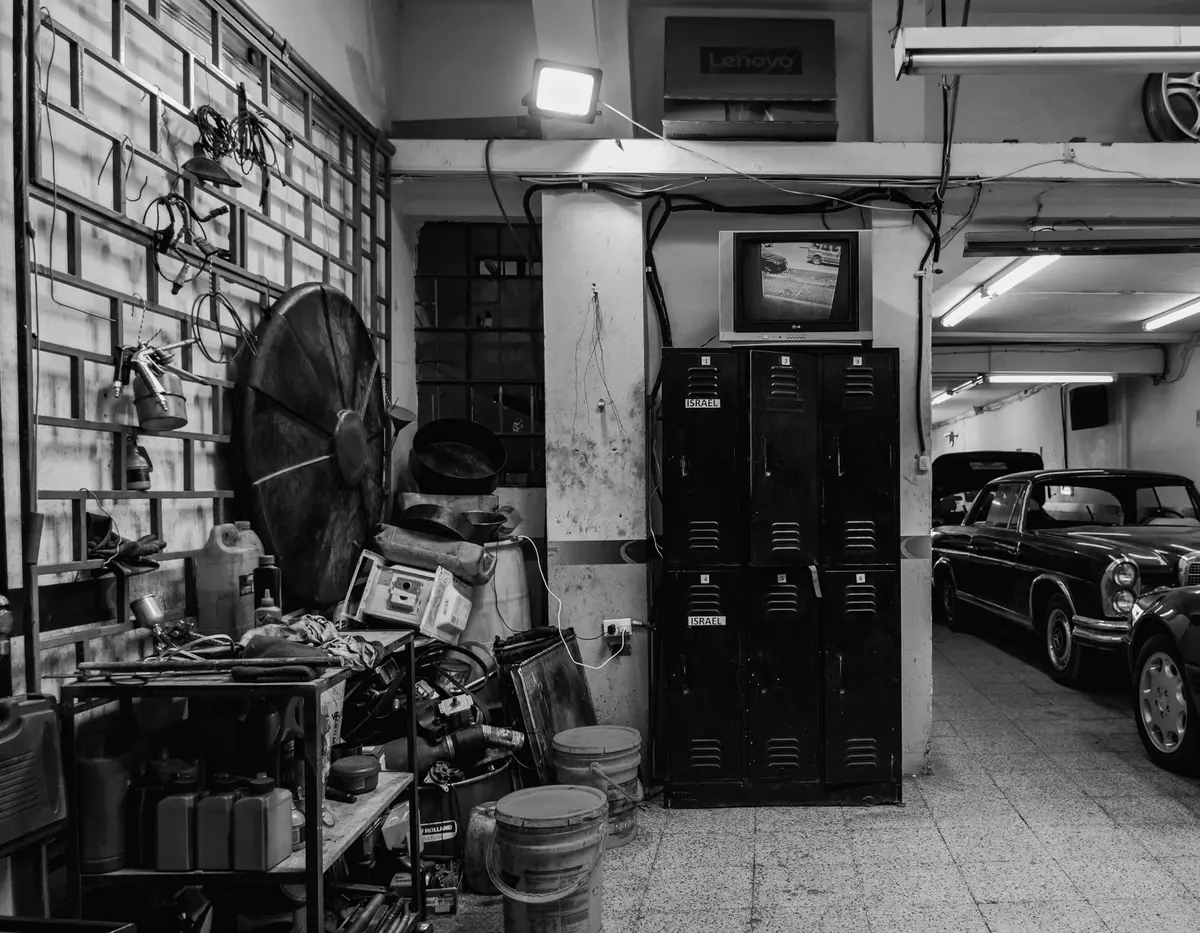 Una vecchia officina con attrezzi e un'auto d'epoca, in bianco e nero